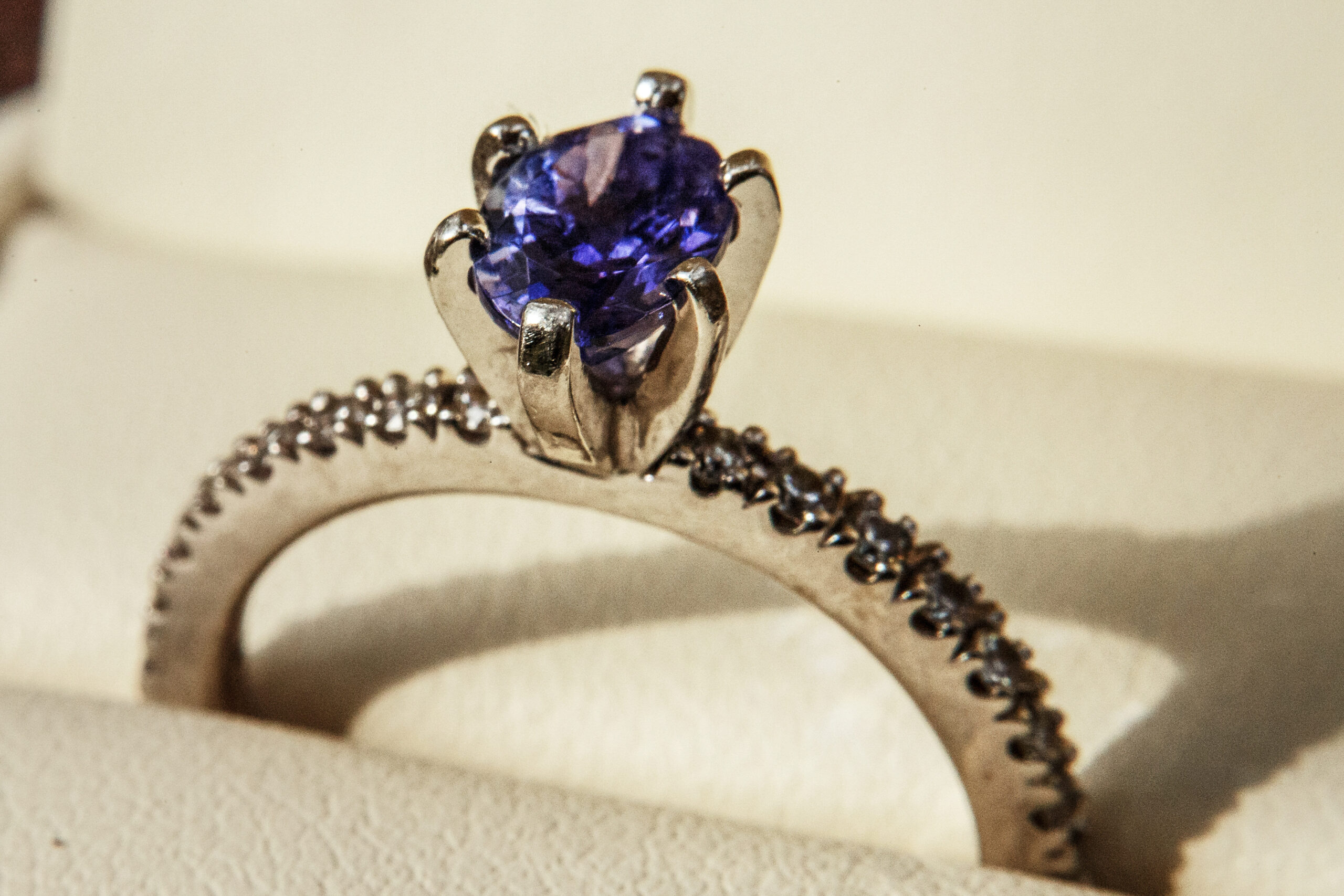 Egagement ring with blue precious stone on white pillow