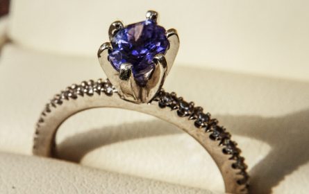 Egagement ring with blue precious stone on white pillow